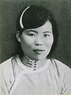 A black-and-white image of a woman in a white shirt, wearing a white headband