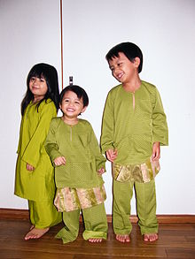 A malay girl and two malay boys dressed in green traditional clothing