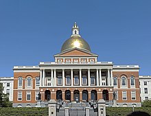 Red brick building with white columns on the façade and a gold dome on the top