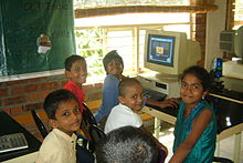 Indian children smiling in front of a computer