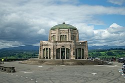 Photograph of a scenic building on a high promontory with an expansive view over a river and canyon