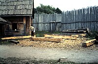 A craftsman uses an adze to square beams, and to recreate 17th-century colonial life