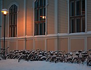 Snowy bicycles in front of library of architecture of Oulu University.