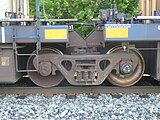 Closeup of a bogie with specially adapted side bearings between two sections of an articulated well car. The axle bearings are not enclosed by an axle box.