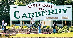 Carberry welcome sign on with a bunch of badasses planting some flowers Highway 5