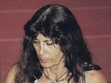 A white woman about 60 years old, black hair with eyes on ground.