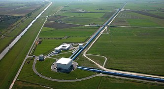 Aerial view, with several white buildings and two long blue tubes forming a right angle