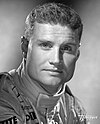 Black and white studio portrait photograph of David Coulthard in racing uniform