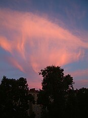 A picture of contorted cirrus cloud shining red in the sunset. Fall streaks (like long thin streamers) descend from the clouds.