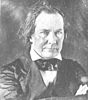 Black and white image of a middle-aged white man dressed in 19th century formal wear.