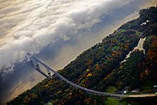 Aerial view of a bridge approaching a fog-covered river