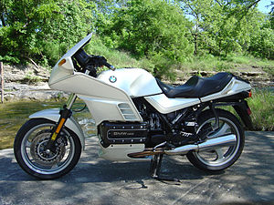 White BMW K1200RS parked in front of a river with trees in the background