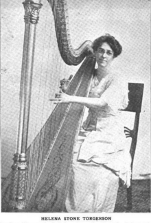 A white woman wearing glasses, her hair in an updo, seated at a harp.