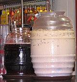 Two large jars of aguas frescas. On the left is a jar of Jamaica and on the right is a jar of horchata.