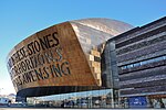 A contemporary building dominated by a copper oxide-treated steel dome, bearing the words "CREU GWYR FEL GWYDR O FFWRNAIS AWEN" / "IN THESE STONES HORIZONS SING".