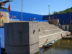 Steps and small boats before a blue screen on an outdoor set.