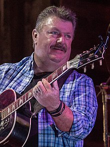 Musician Joe Diffie holding an acoustic guitar.