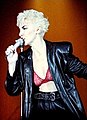 Scottish singer Annie Lennox of the Eurythmics in 1986. She is wearing high-waisted trousers, a black leather coat with a pink lace bra underneath.