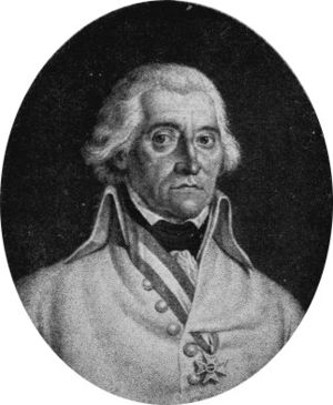 Portrait of white haired man wearing ribbon around his neck, through jacket button hole, with a square-shaped cross.