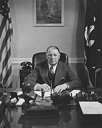 Male civilian sitting at a desk, with pen in hand