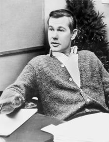 A black-and-white image of Johnny Carson sitting at a desk.