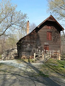 Photograph of a three-story wooden grist mill with a ramp leading to the front door