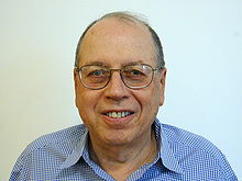 Shoulder high portrait of man in his sixties in a checked shirt with a blank white background