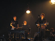 Three men on stage playing instruments