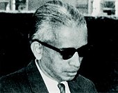 A black and white photograph of man wearing black glasses