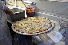 Characteristically large New York–style pizza ready to go into the oven