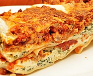 Close-up profile view of a lasagne casserole, showing the layers of sauce, cheese and other ingredients