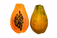 Photograph showing a papaya in cross section, with orange flesh and numerous black seeds