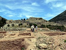 Wide shot; several open graves can be seen with the citadel of Mycenae behind