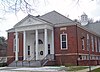 A brick building whose front section has a white triangular roof supported by columns. The inscription on the front reads "Bendheim West Greenwich Civic Center"