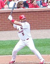 A man with feet spread apart holding a baseball bat in the air