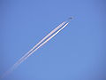 A Boeing 747 of Japan Airlines displays contrails.