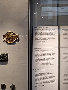 A Gold Parthian Belt Buckle, dated 1st to 3rd century AD, with an eagle in the centre holding a sheep or goat. On the left-hand side of the eagle's Brest is what appears to be a heart symbol. There is either pigment or a stone inlaid inside the heart symbol.