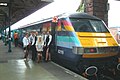 Catering staff dressed for a charity event, alongside a 'one'-branded train at Norwich station