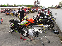 Pre-race assembly area[2] adjacent to startline showing machines with tyre warmers plugged into wall-mounted electrical outlets