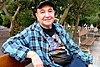 A man wearing a cap is sitting on a bench