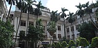 Large white columned building, with palm trees in front