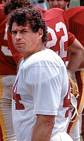 An American football player looks to his left in the direction of the camera. He is not wearing his helmet.