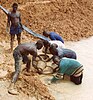 A group of diamond miners panning at the edge of a man-made pond