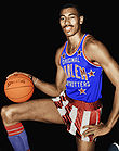 Man kneeling and holding a basketball in a Harlem Globetrotters uniform