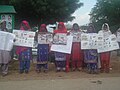 Women, dressed in ornate shalwars, in a picket line.