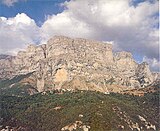 A small village on the top of a hill and huge cliffs on the background