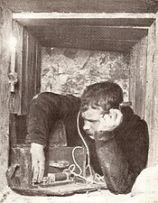 World War I soldier in a dugout with headphones listening to a radio