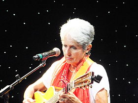 Baez at microphone, playing guitar, in sleeveless top