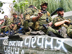 Soldiers sitting on tank with white graffiti