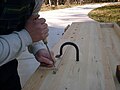 A hold fast being used to affix a board to the benchtop for chiseling dovetails